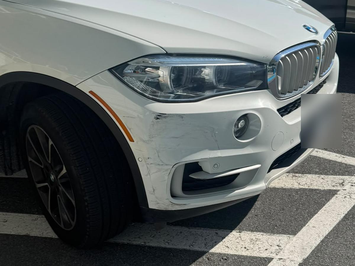 White BMW X5 with a scraped front bumper